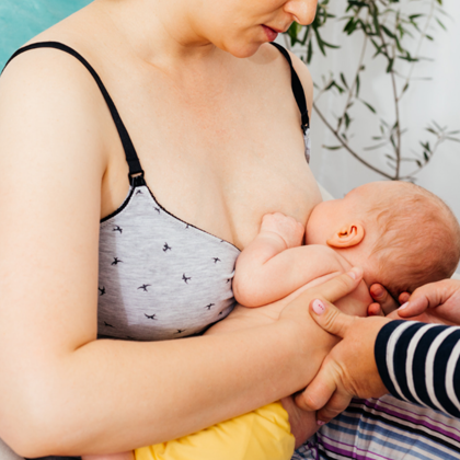 A close up view of a pregnant woman holding her belly, being that a child is developing.